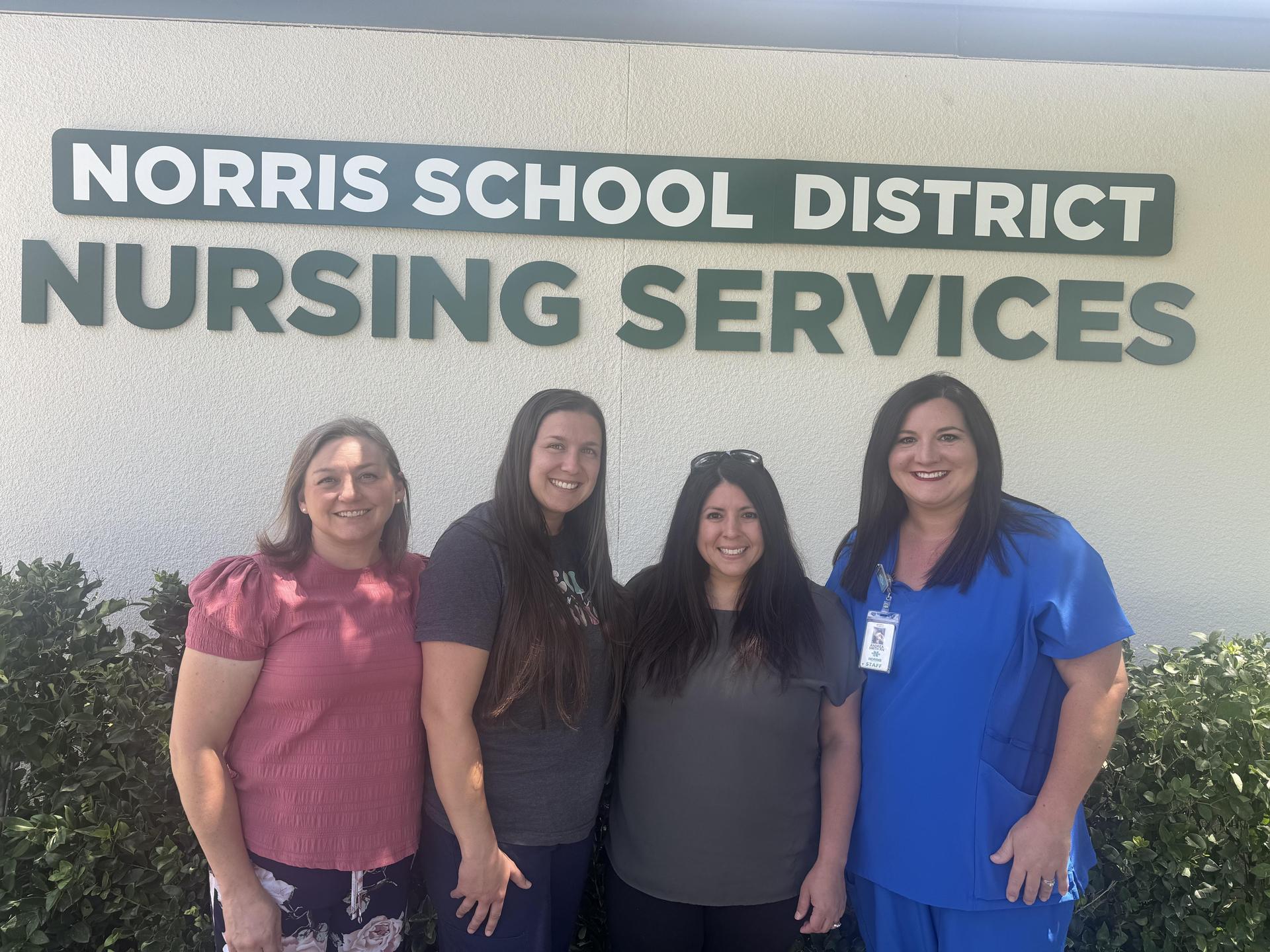 Norris School District Nursing Services team standing together in front of the Nursing Services building signage.